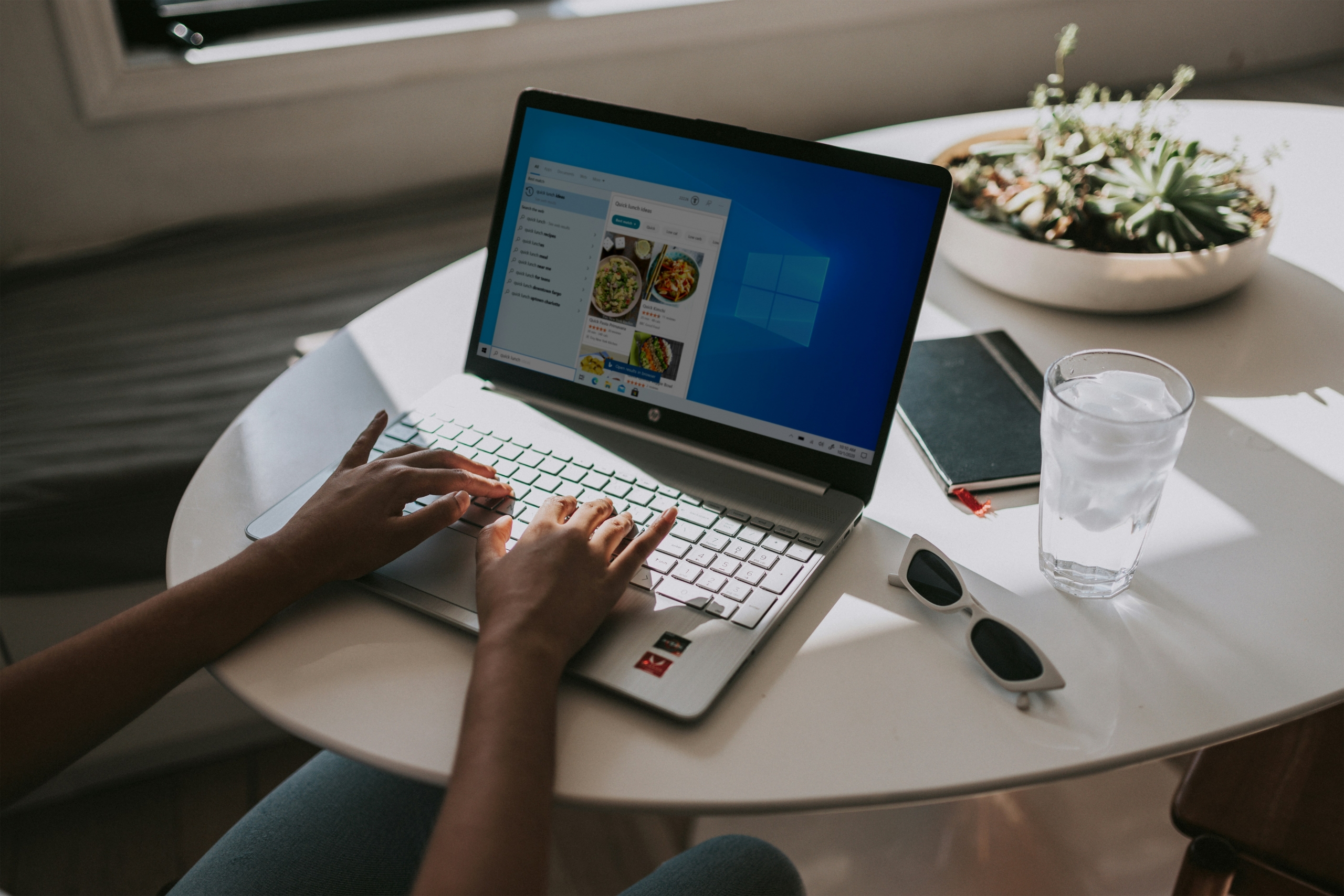 Hands typing on laptop showing the Windows UI Hands typing on laptop showing the Windows UI