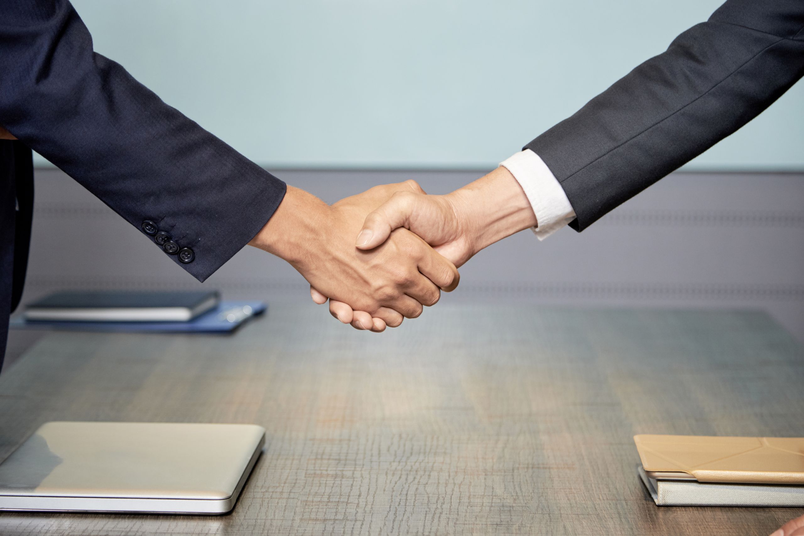 Close up of two people wearing suits shaking hands over table. Close up of two people wearing suits shaking hands over table.